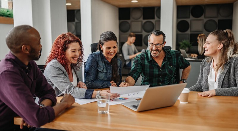 five team members working around a table and laptop