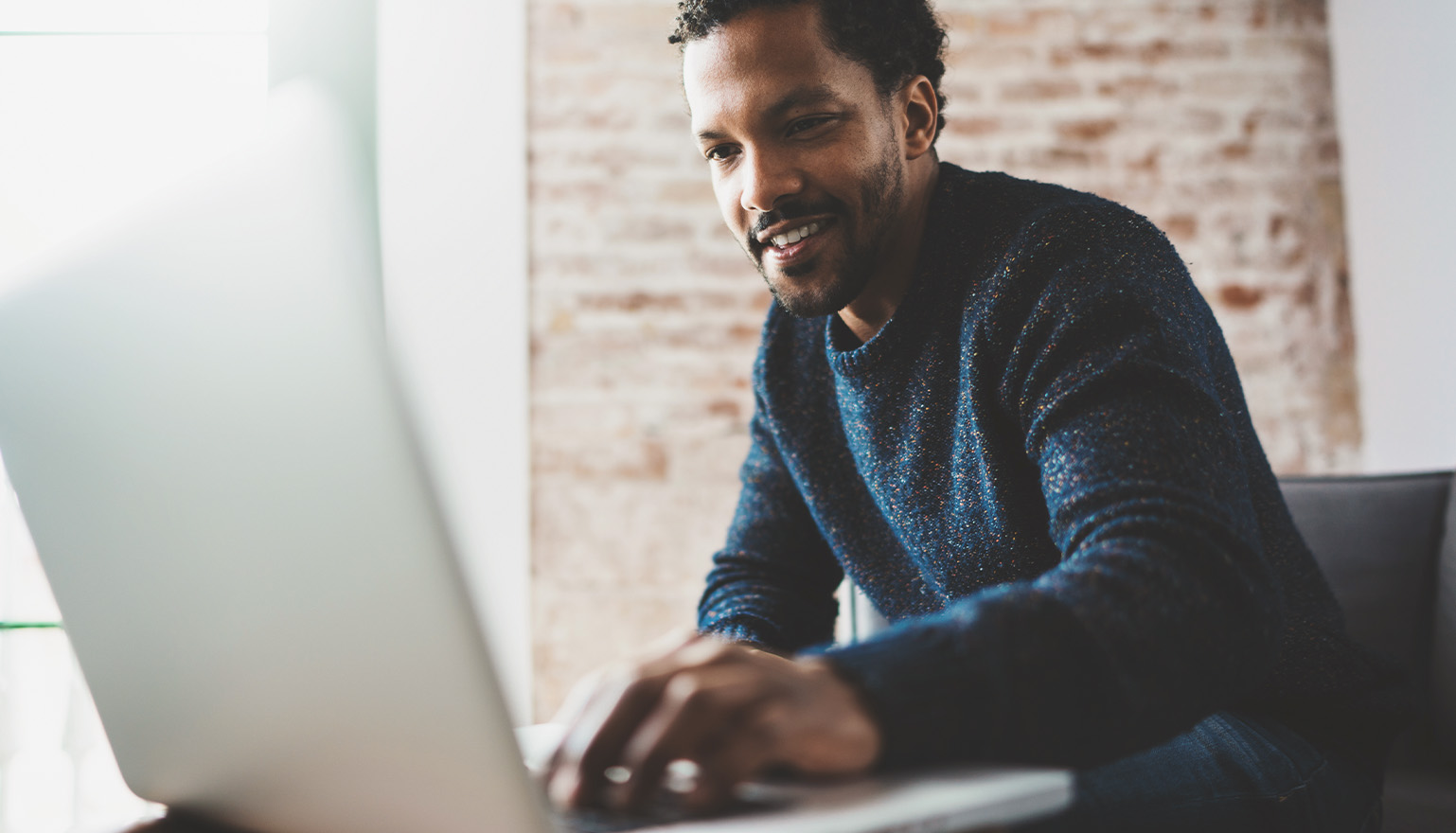 man in blue sweater working on laptop