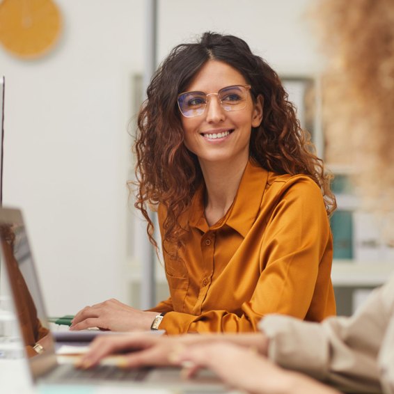 two woman working together on their laptops