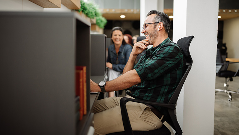 man laughing at his desk with headphones in