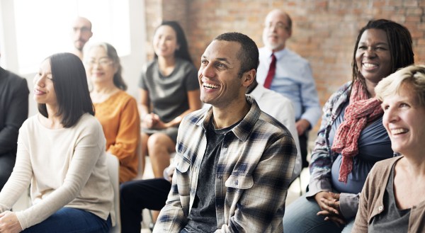 Image of a diverse group of people sitting in a room attending a conference meeting.
