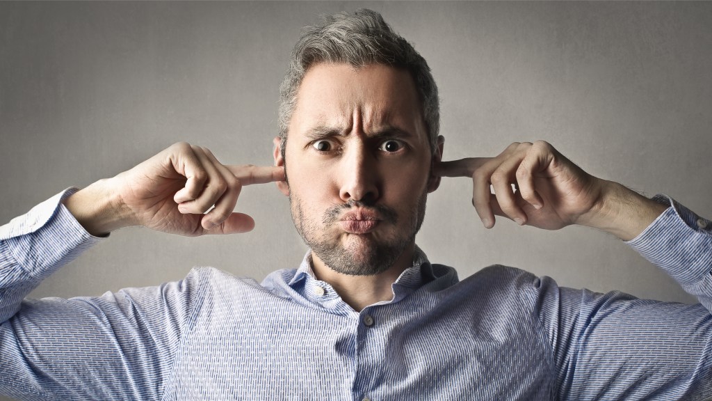 A picture of a man from the shoulders up with his fingers in his ears and a pouty look on his face, refusing to listen to what his accounting firm needs from him.